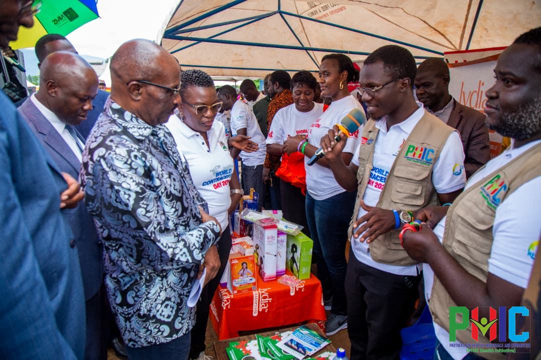 PHIC team engaging Ministry of Health leaders and guests at the PHIC exhibition table during World Contraception Day 2026 in Namisindwa District
