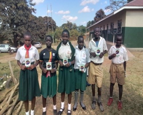 Pupils photo holding IEC books after the IEC session on 26th June 2024 At Kasengejje church of Uganda primary school